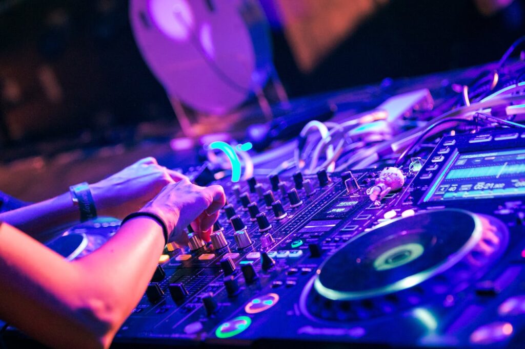 pexels photo 8131392 DJ uses a digital mixer to create music at a lively nightclub event.